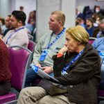 Crwod of people seated listening closely at a meeting