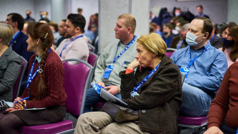 Crwod of people seated listening closely at a meeting