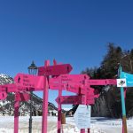 Big group confusing direction signs for different trails near a ski lodge