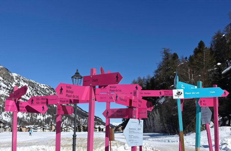 Big group confusing direction signs for different trails near a ski lodge