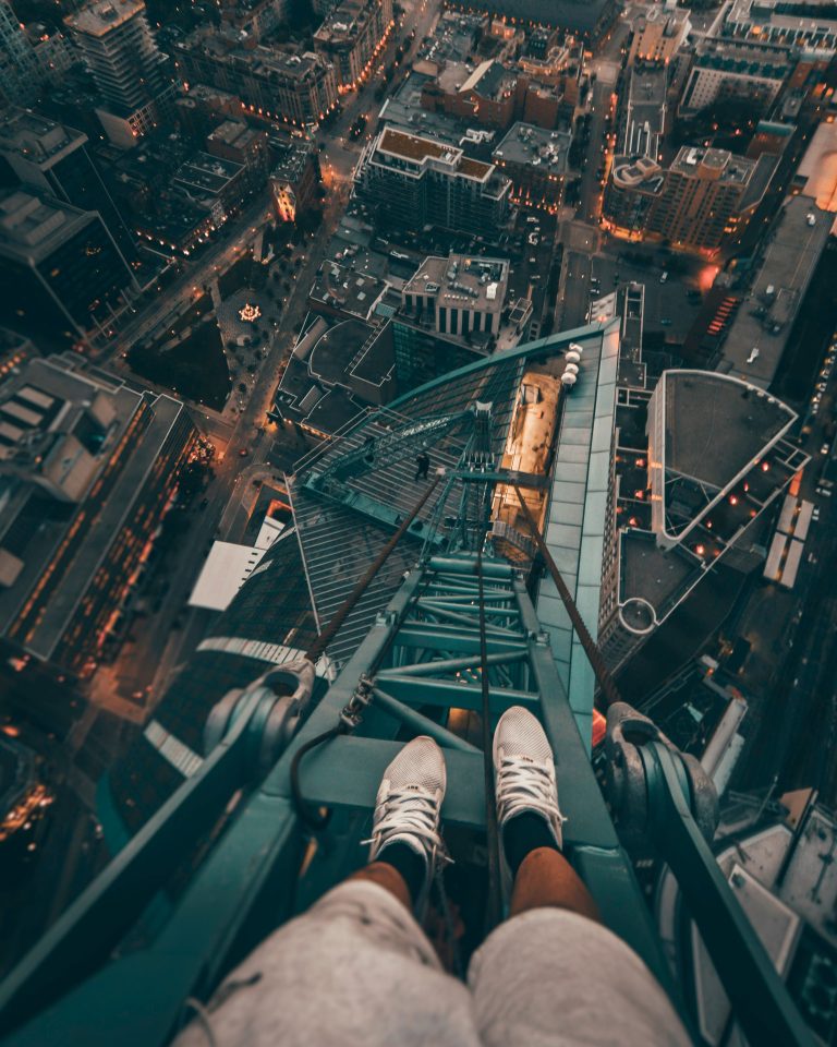 person looking down at their feet and then down a very tall, steep tower