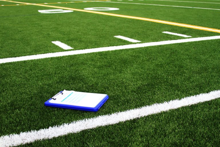 Playbook clipboard sitting next to the 50-yard line on a football field