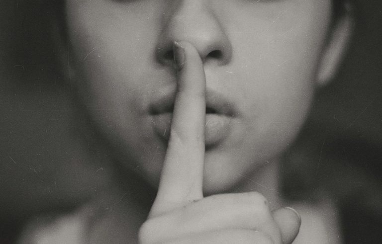 Index finger over the mouth of a fashion model in black and white