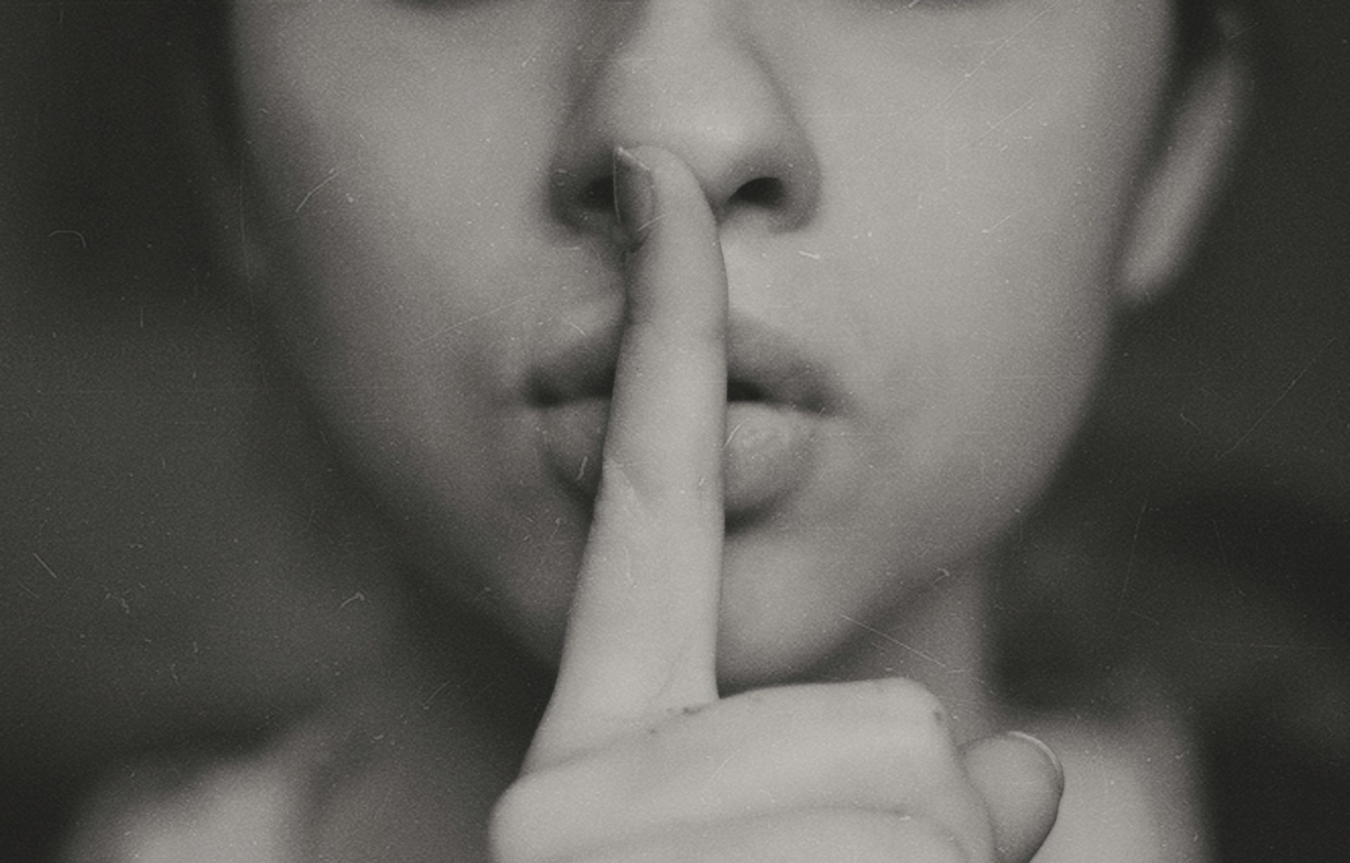 Index finger over the mouth of a fashion model in black and white