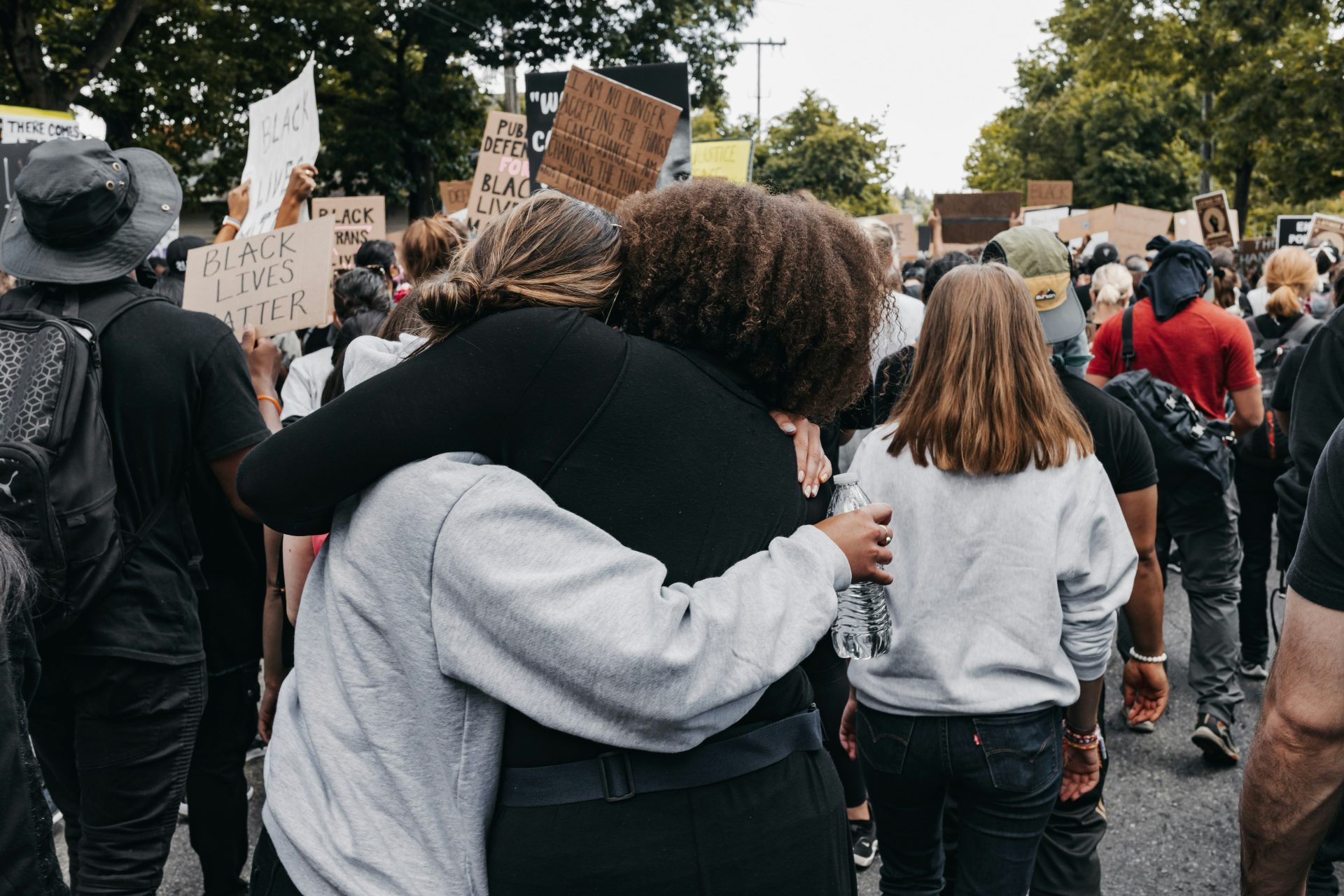 Photo of a large protest with two women hugging each other in solidarity