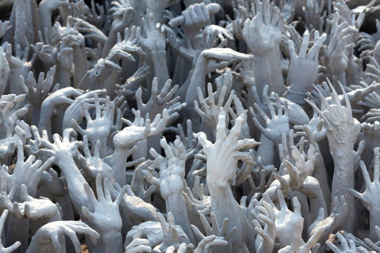 Densely packed grasping hands and claws reaching upwards