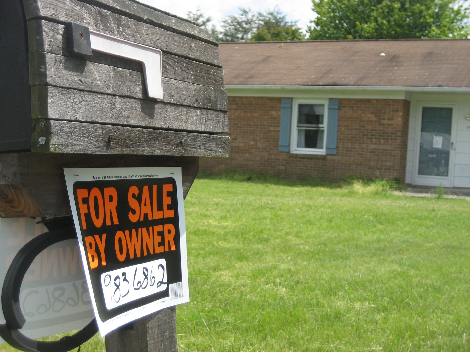 "For Sale by Owner" sign on mailbox in front of a fairly rough looking house