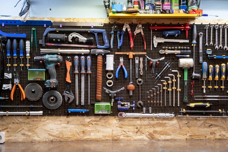 A very large pegboard cabinet on a wall covered with lots and lots of tools all neatly laid out.