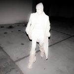 Black and white reverse silhouette of a woman with a crutch, perhaps an infrared or enhanced night vision picture