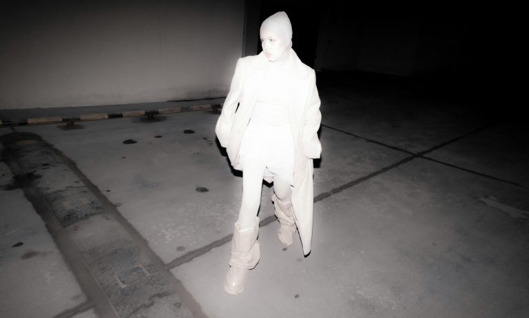 Black and white reverse silhouette of a woman with a crutch, perhaps an infrared or enhanced night vision picture
