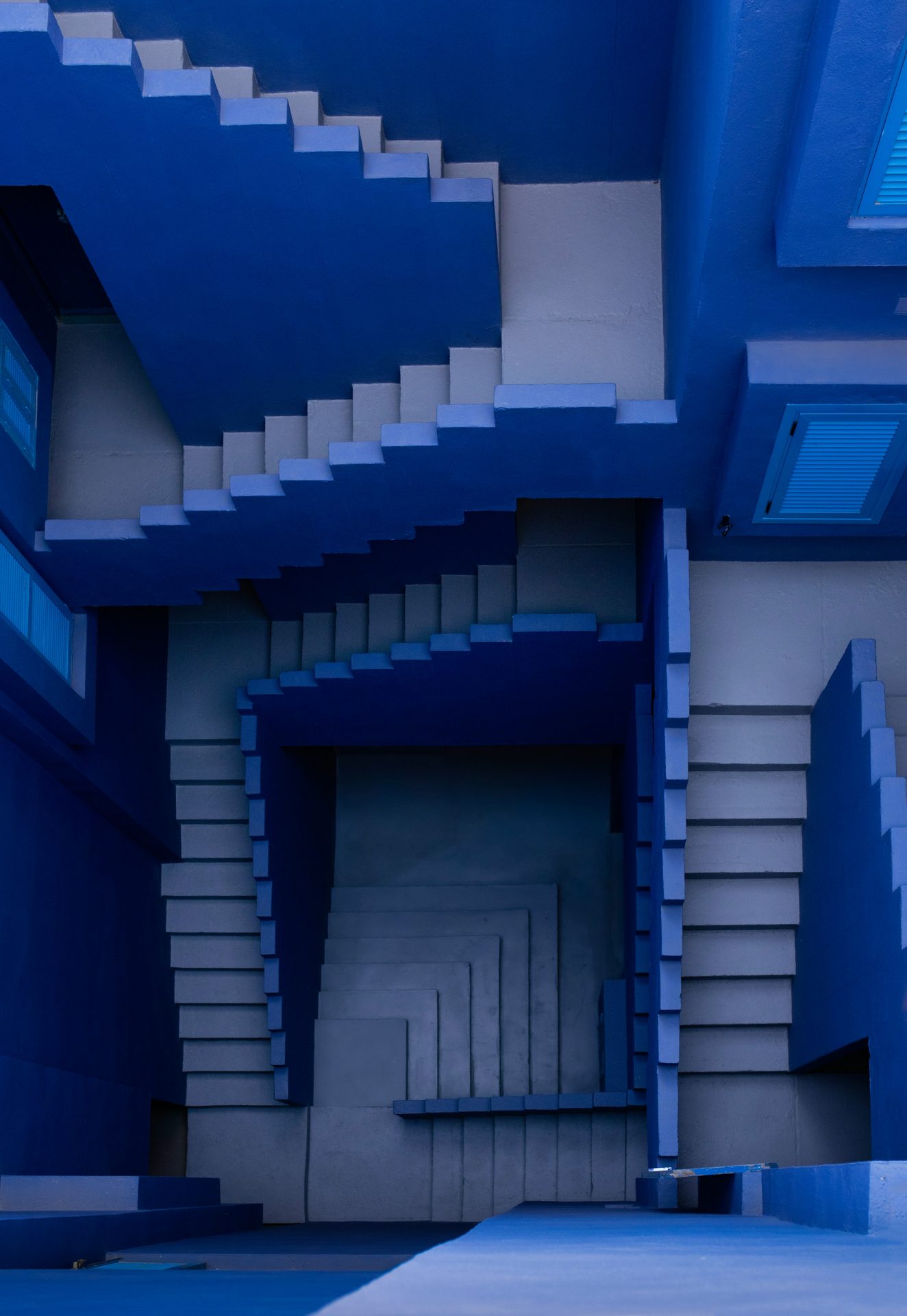 Looking down at a blue, maze-like set of staircases