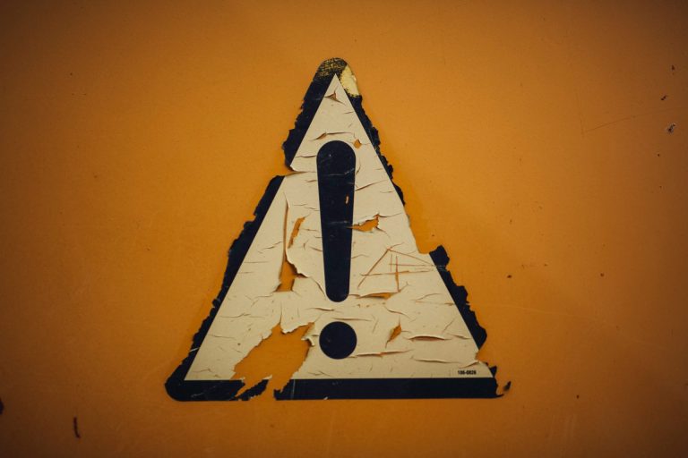 Triangular heavily weathered street sign with a large Exclamation Point.