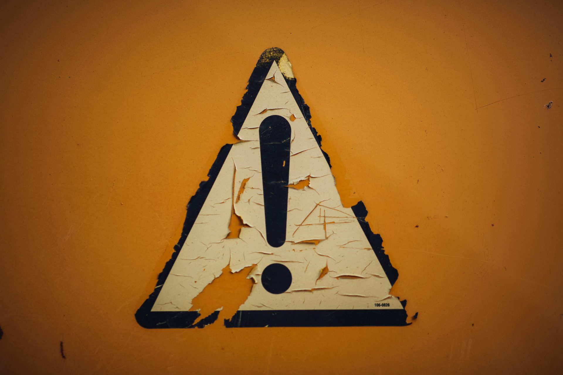 Triangular heavily weathered street sign with a large Exclamation Point.