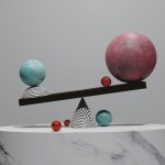 A complicated balance of Large and small spheres on top of a cone on a pedestal.