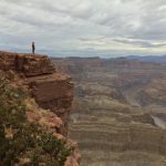 A hiker in distance looking out across a very wide canyon