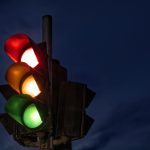 Traffic light at night with the red, yellow, and green lights all illuminated