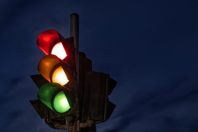 Traffic light at night with the red, yellow, and green lights all illuminated