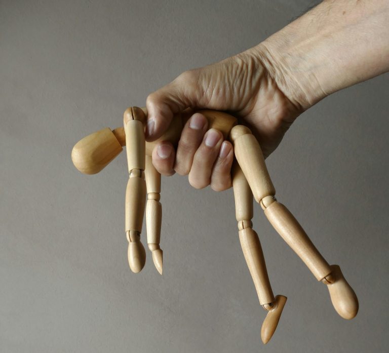 Close up of a hand holding a wooden mannequin