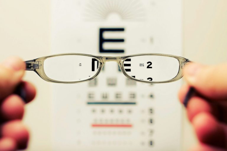 Looking through a pair of glasses at an eye test chart with area outside of lenses blurred