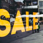 Big Bold SALE in Yellow in front of an urban street scene